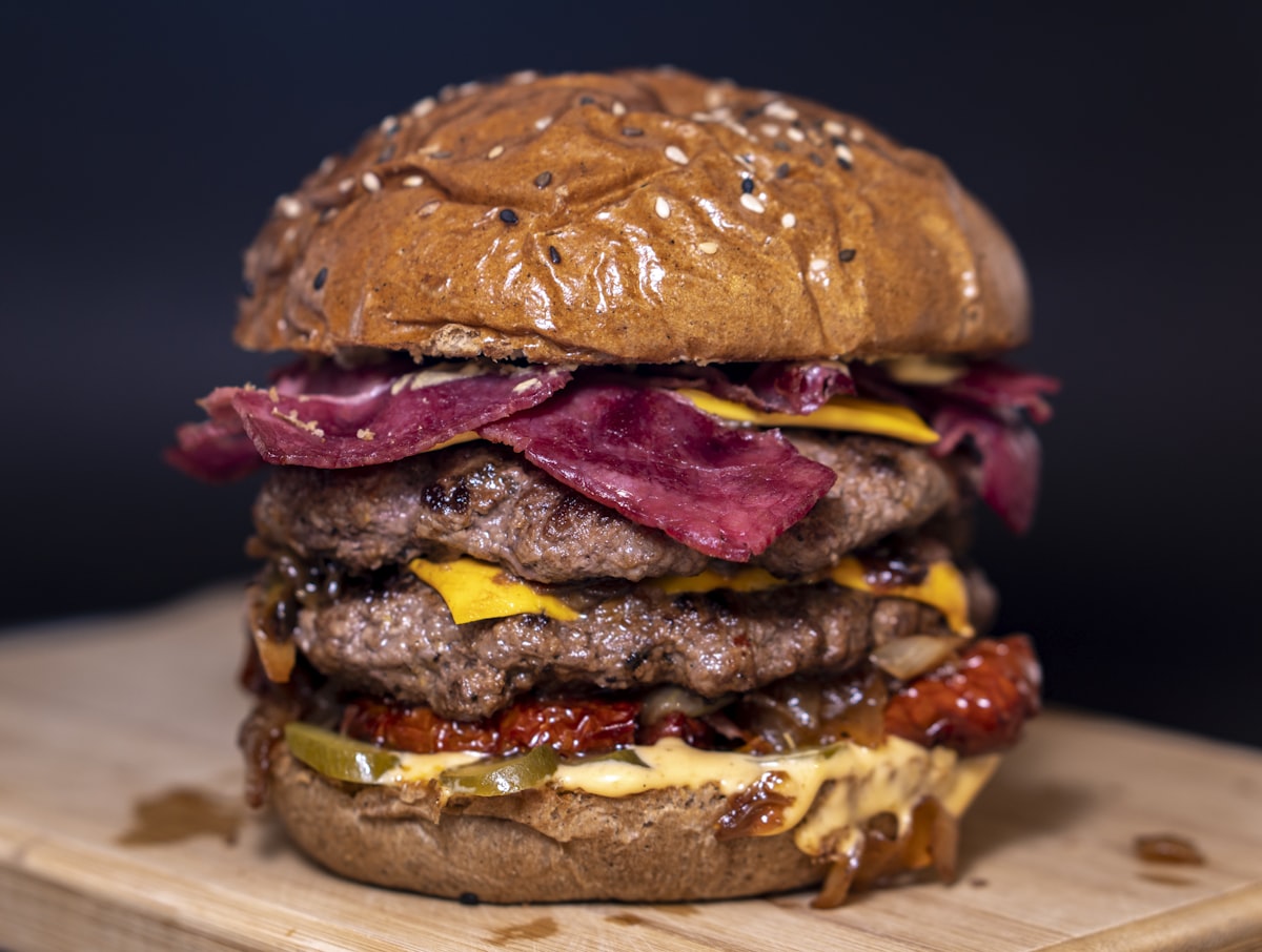 Triple-stack burger with crispy strips on a black background
