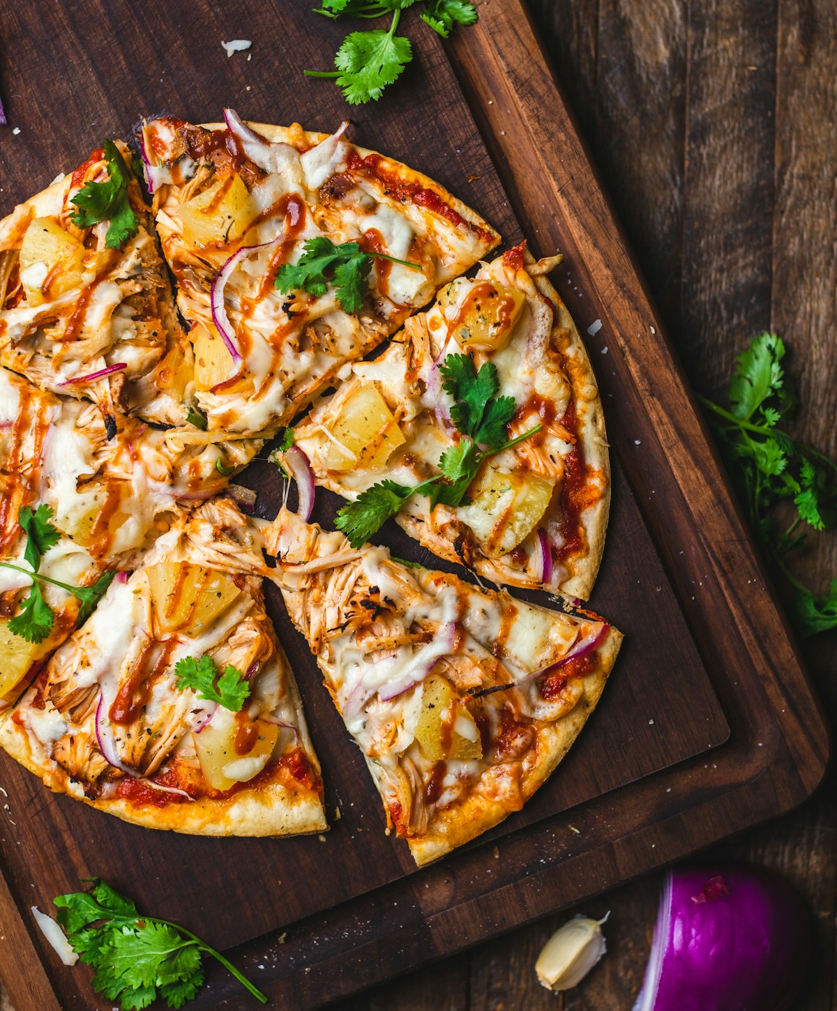 Smoky BBQ chicken pizza on a dark wooden board